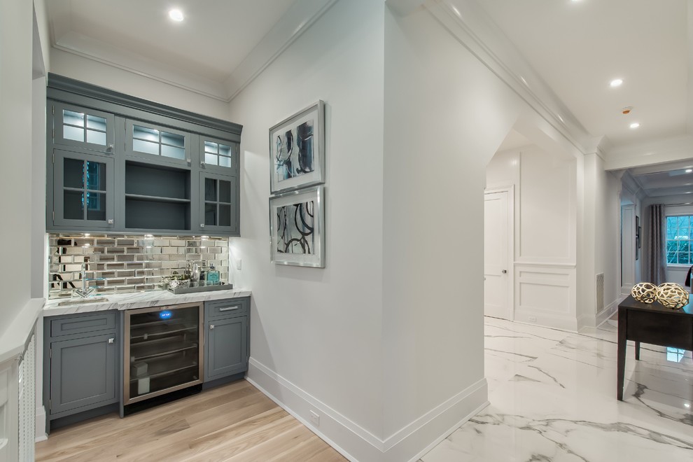 Eat-in kitchen - mid-sized traditional u-shaped light wood floor and beige floor eat-in kitchen idea in New York with an undermount sink, flat-panel cabinets, white cabinets, marble countertops, white backsplash, ceramic backsplash, stainless steel appliances, an island and white countertops