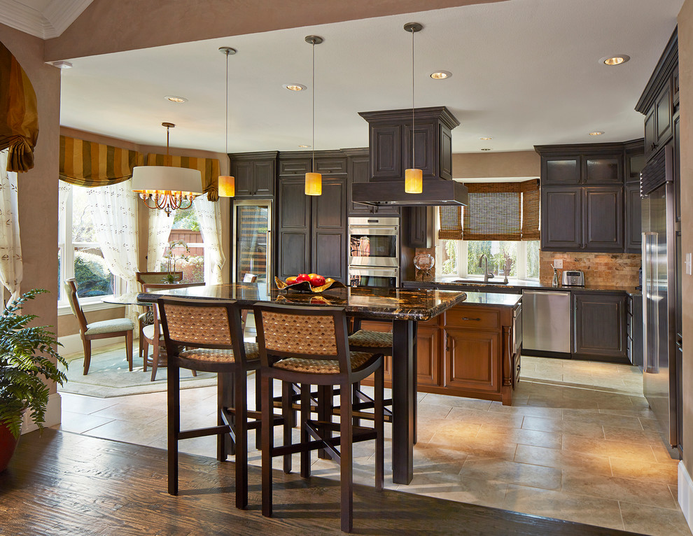 Example of a large transitional l-shaped ceramic tile and brown floor open concept kitchen design in Dallas with an undermount sink, distressed cabinets, granite countertops, multicolored backsplash, stone tile backsplash, stainless steel appliances, recessed-panel cabinets and two islands