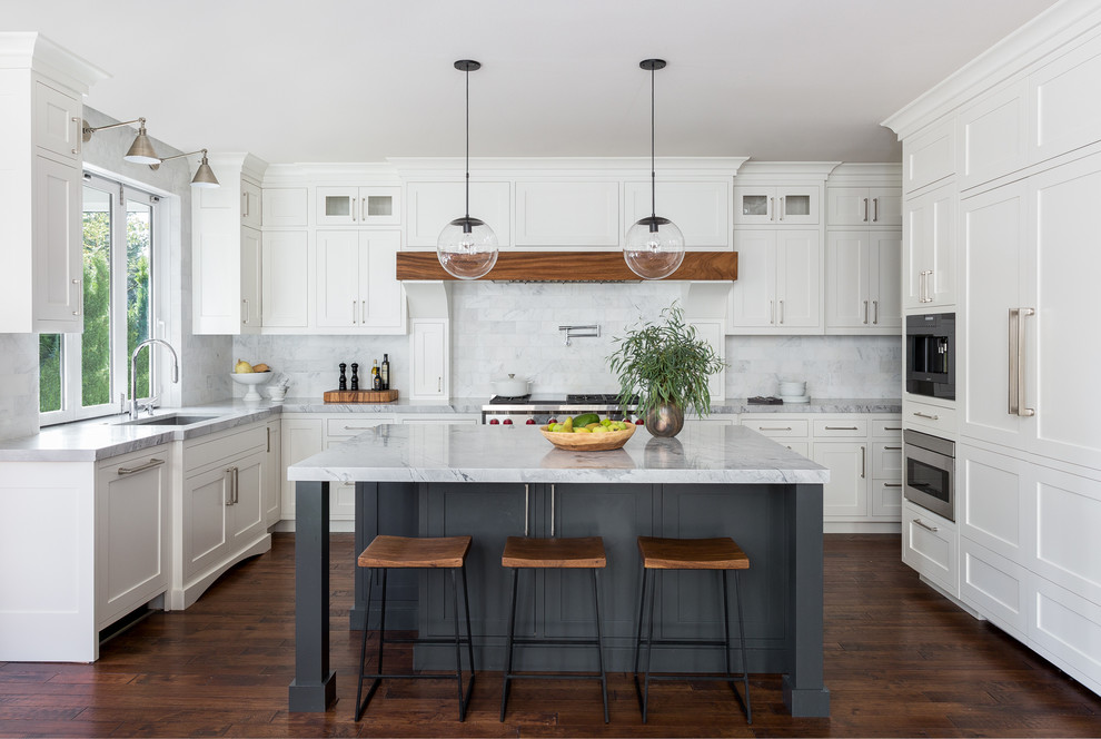 Idée de décoration pour une grande cuisine ouverte encastrable et bicolore tradition en U avec un évier encastré, un placard à porte shaker, des portes de placard blanches, une crédence blanche, une crédence en marbre, parquet foncé, îlot, un sol marron, plan de travail en marbre et un plan de travail gris.