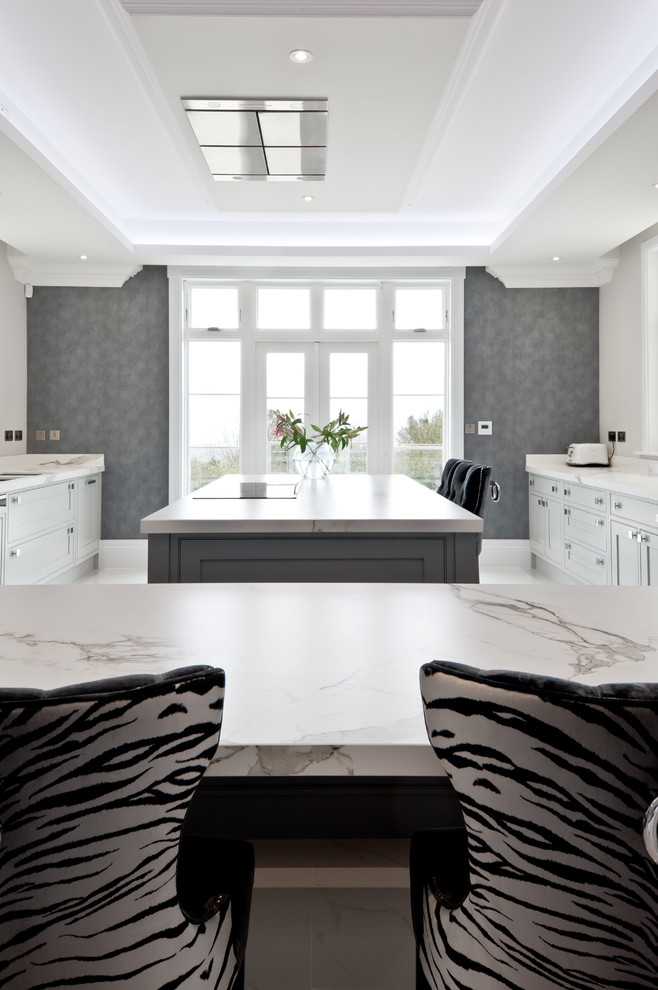 This is an example of a large traditional kitchen/diner in Kent with a submerged sink, beaded cabinets, grey cabinets, composite countertops, integrated appliances, an island and grey floors.