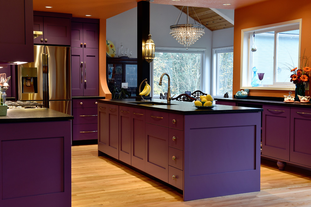 ポートランドにある高級な広い地中海スタイルのおしゃれなキッチン (アンダーカウンターシンク、シェーカースタイル扉のキャビネット、紫のキャビネット、クオーツストーンカウンター、オレンジのキッチンパネル、セラミックタイルのキッチンパネル、シルバーの調理設備、淡色無垢フローリング、茶色い床、黒いキッチンカウンター) の写真