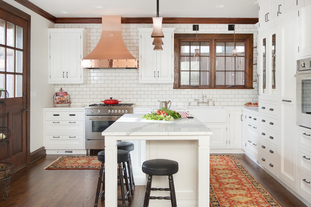Bild på ett avskilt, stort vintage l-kök, med en rustik diskho, luckor med infälld panel, vita skåp, marmorbänkskiva, vitt stänkskydd, stänkskydd i tunnelbanekakel, rostfria vitvaror, mörkt trägolv och en köksö