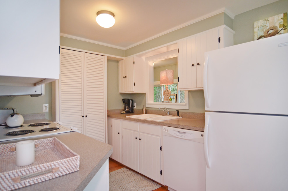 Example of a small beach style galley light wood floor eat-in kitchen design in Seattle with a double-bowl sink, beaded inset cabinets, white cabinets, laminate countertops and white appliances