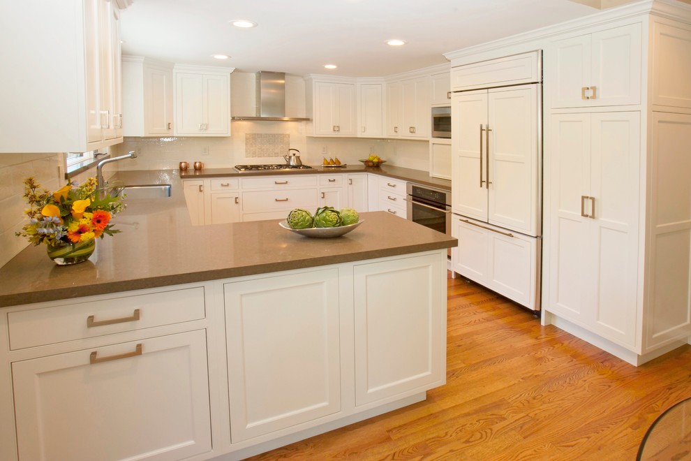 Inspiration for a large timeless u-shaped light wood floor enclosed kitchen remodel in San Francisco with an undermount sink, shaker cabinets, white cabinets, quartzite countertops, white backsplash, ceramic backsplash, stainless steel appliances and a peninsula