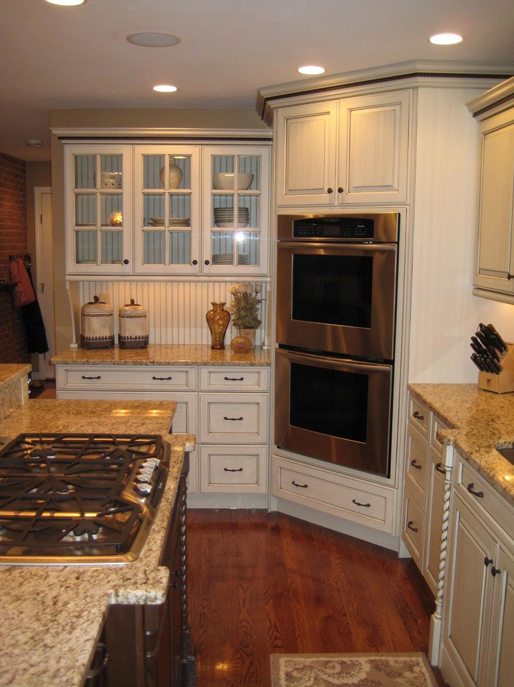 Ejemplo de cocina tradicional con fregadero bajoencimera, armarios con paneles con relieve, puertas de armario blancas, encimera de granito y electrodomésticos de acero inoxidable