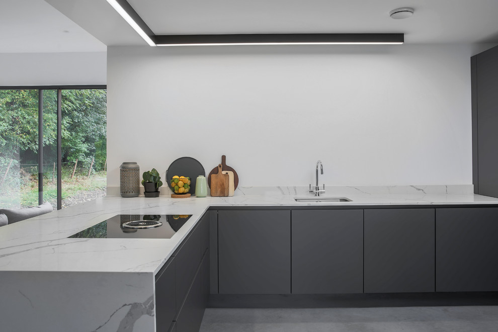Exempel på ett mellanstort modernt vit vitt kök, med en integrerad diskho, släta luckor, grå skåp, marmorbänkskiva, vitt stänkskydd, stänkskydd i marmor, integrerade vitvaror, betonggolv, en halv köksö och grått golv