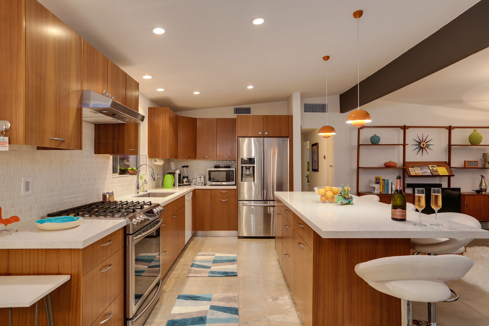 Mid-sized mid-century modern ceramic tile eat-in kitchen photo in Los Angeles with a double-bowl sink, flat-panel cabinets, light wood cabinets, soapstone countertops, white backsplash, mosaic tile backsplash, stainless steel appliances and an island