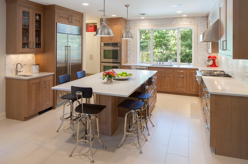 Bild på ett funkis u-kök, med en undermonterad diskho, skåp i shakerstil, skåp i mellenmörkt trä, vitt stänkskydd, rostfria vitvaror och en köksö