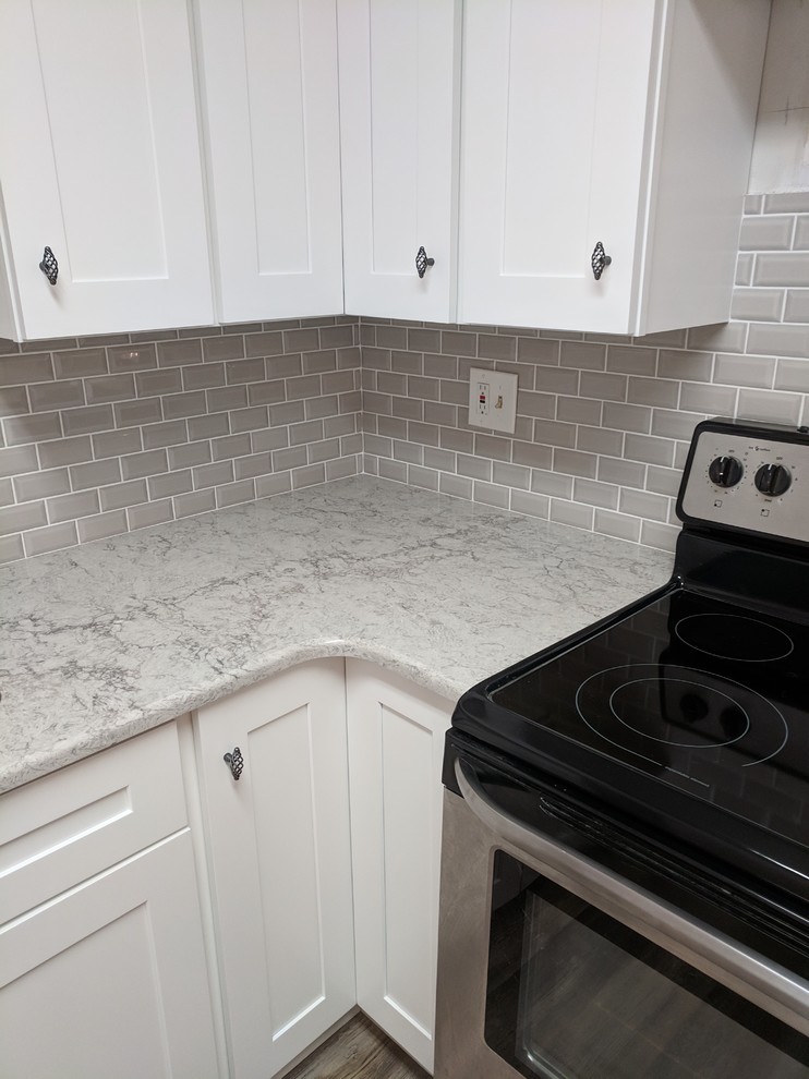 Exempel på ett avskilt, litet modernt flerfärgad flerfärgat u-kök, med en undermonterad diskho, skåp i shakerstil, vita skåp, bänkskiva i kvartsit, grått stänkskydd, stänkskydd i tunnelbanekakel, rostfria vitvaror, vinylgolv och flerfärgat golv