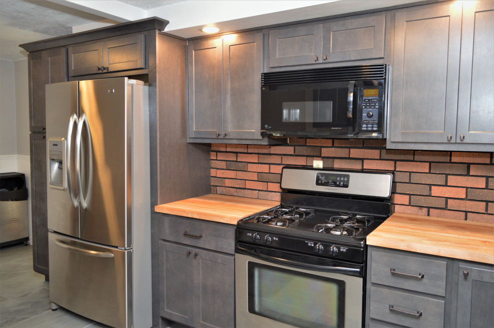 Bild på ett mellanstort lantligt brun brunt kök, med en undermonterad diskho, skåp i shakerstil, grå skåp, träbänkskiva, rött stänkskydd, stänkskydd i tegel, rostfria vitvaror, skiffergolv och grått golv