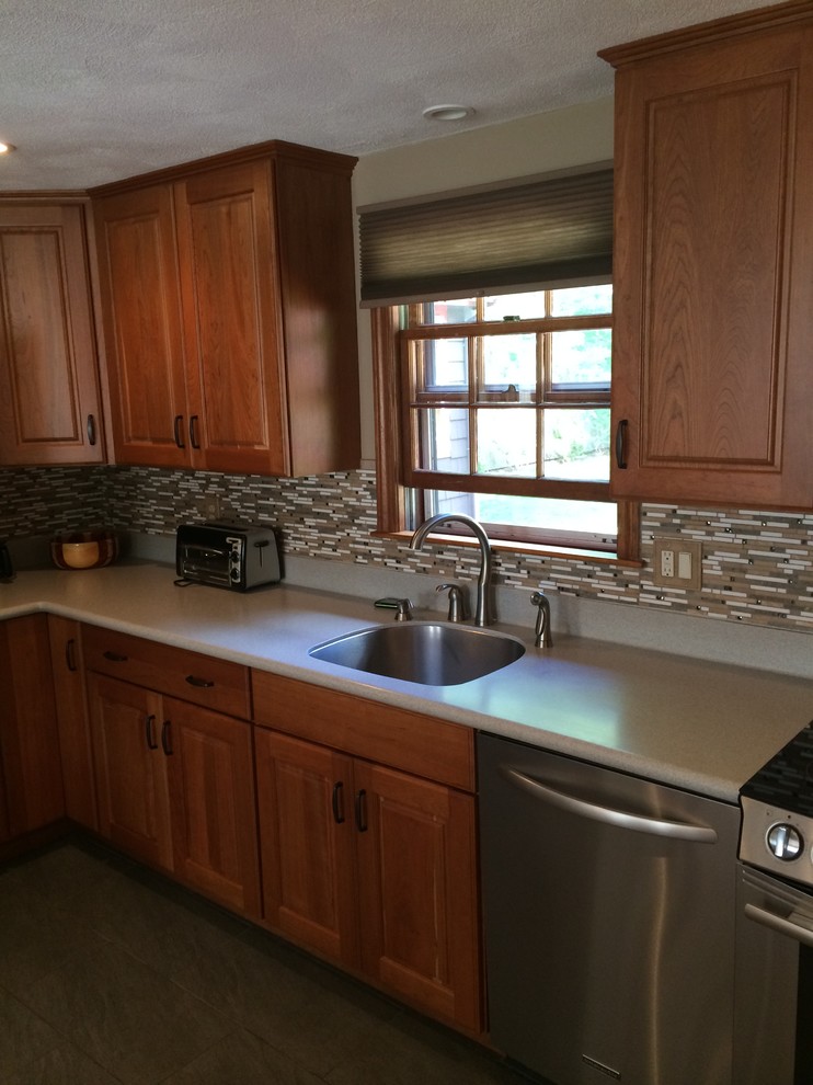 Mid-sized elegant l-shaped terrazzo floor eat-in kitchen photo in Boston with a single-bowl sink, raised-panel cabinets, medium tone wood cabinets, quartz countertops, brown backsplash, glass tile backsplash, stainless steel appliances and a peninsula