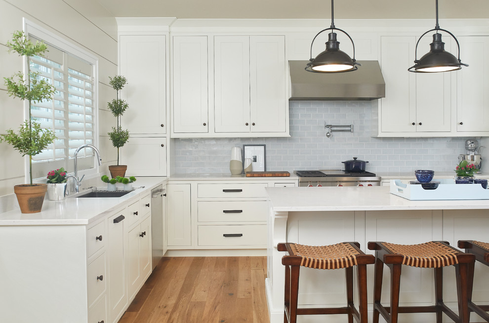 Design ideas for a traditional kitchen in Grand Rapids with white cabinets, blue splashback, stainless steel appliances and an island.