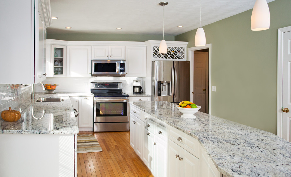 Inspiration for a mid-sized modern l-shaped light wood floor eat-in kitchen remodel in Boston with a double-bowl sink, raised-panel cabinets, white cabinets, granite countertops, white backsplash, subway tile backsplash, stainless steel appliances and an island
