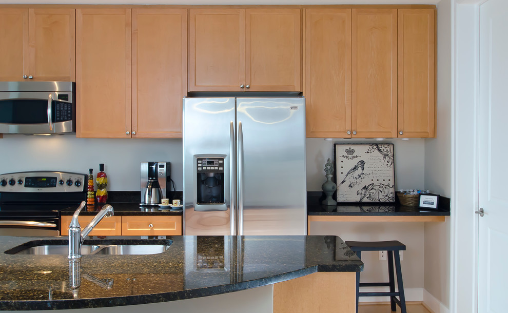 Exempel på ett mellanstort modernt kök, med en dubbel diskho, luckor med infälld panel, skåp i mörkt trä, granitbänkskiva, rostfria vitvaror, ljust trägolv och en köksö