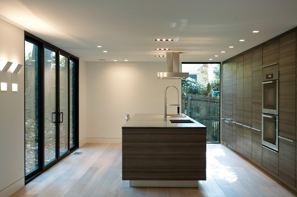 Immagine di una cucina parallela minimalista con ante lisce, ante in legno bruno e elettrodomestici in acciaio inossidabile