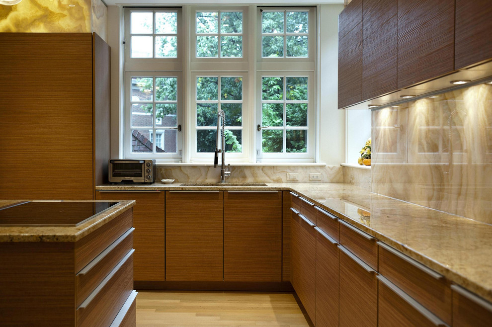 Moderne Küche mit flächenbündigen Schrankfronten, hellbraunen Holzschränken und Rückwand aus Stein in Sonstige
