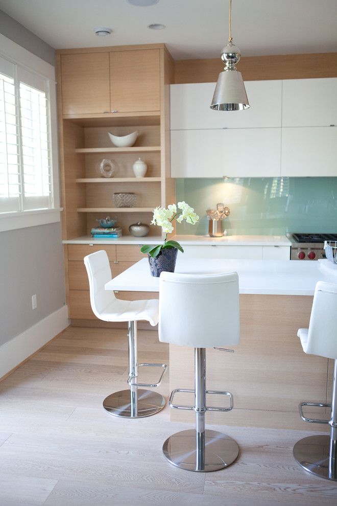 Moderne Wohnküche mit flächenbündigen Schrankfronten, weißen Schränken, Küchenrückwand in Blau und Glasrückwand in Vancouver