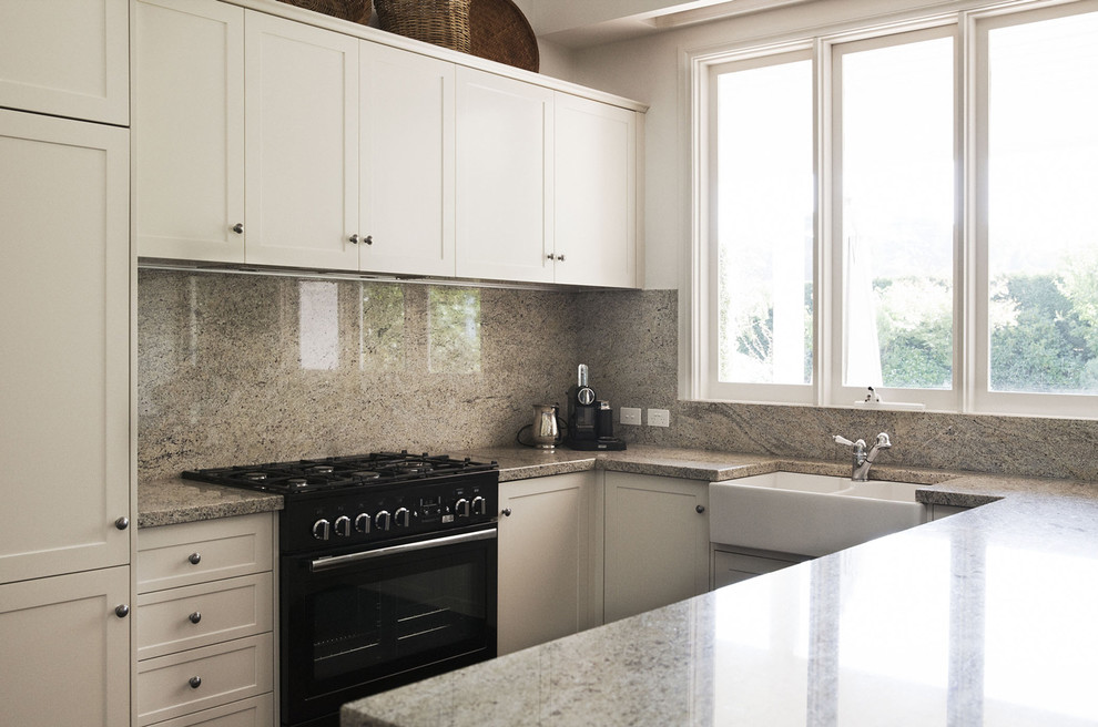 Источник вдохновения для домашнего уюта: кухня в современном стиле с фасадами с утопленной филенкой, белыми фасадами, черной техникой, серым фартуком и фартуком из каменной плиты
