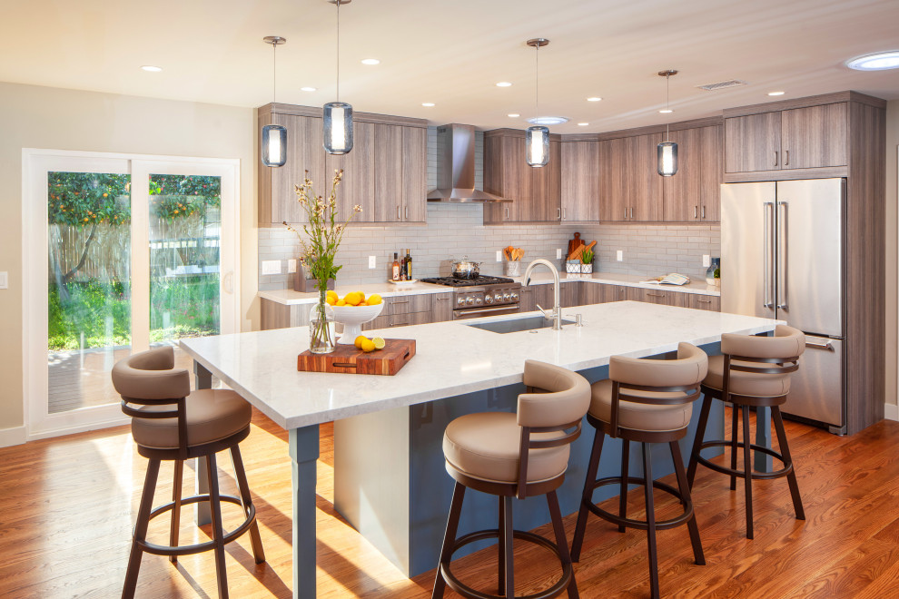サンディエゴにあるコンテンポラリースタイルのおしゃれなキッチン (フラットパネル扉のキャビネット、中間色木目調キャビネット、白いキッチンパネル、サブウェイタイルのキッチンパネル、無垢フローリング、茶色い床、白いキッチンカウンター) の写真