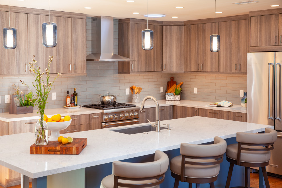 Große Moderne Wohnküche in L-Form mit Unterbauwaschbecken, hellen Holzschränken, Küchengeräten aus Edelstahl, Kücheninsel, braunem Boden, weißer Arbeitsplatte, flächenbündigen Schrankfronten, Quarzwerkstein-Arbeitsplatte, Küchenrückwand in Blau, Rückwand aus Porzellanfliesen und braunem Holzboden in San Diego