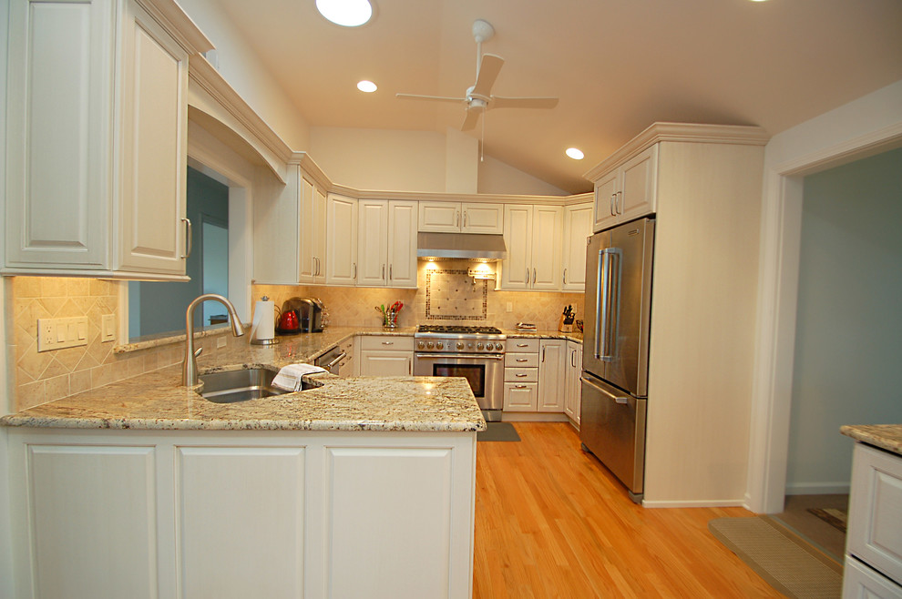 Foto på ett mellanstort vintage kök, med en undermonterad diskho, luckor med upphöjd panel, vita skåp, granitbänkskiva, beige stänkskydd, stänkskydd i keramik, rostfria vitvaror, ljust trägolv och en halv köksö