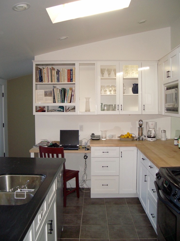 Small transitional u-shaped ceramic tile kitchen photo in San Francisco with an undermount sink, recessed-panel cabinets, white cabinets, wood countertops, mirror backsplash, black appliances and an island