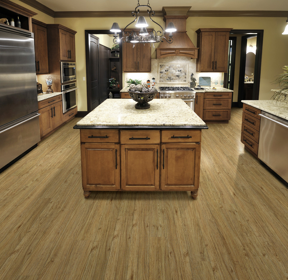 Example of a large classic galley vinyl floor and brown floor open concept kitchen design in Los Angeles with recessed-panel cabinets, medium tone wood cabinets, granite countertops, multicolored backsplash, stone tile backsplash, stainless steel appliances and an island