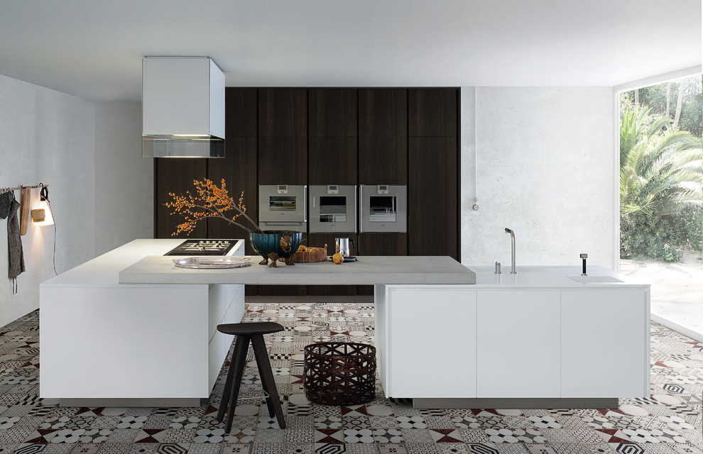 Modelo de cocina actual con electrodomésticos de acero inoxidable, una isla, armarios con paneles lisos y puertas de armario blancas