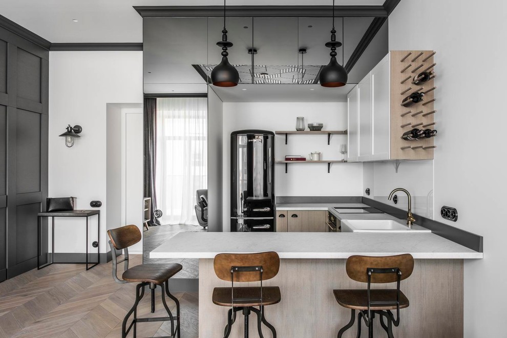 Example of a trendy u-shaped light wood floor and beige floor kitchen design in DC Metro with a farmhouse sink, white backsplash, glass sheet backsplash, black appliances, a peninsula and white countertops