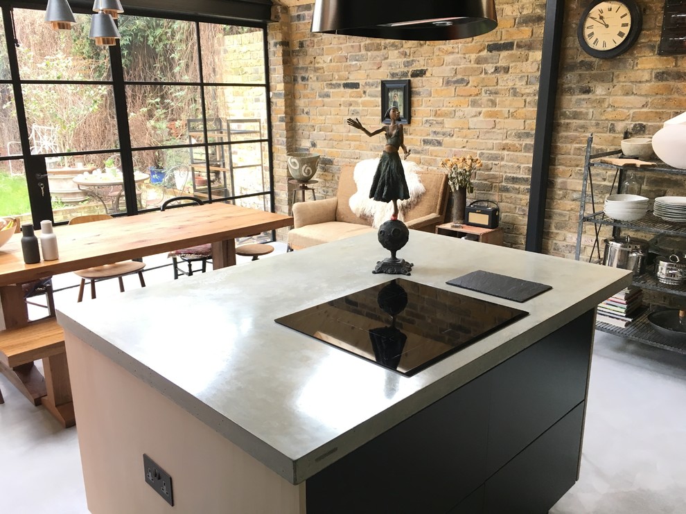 Design ideas for a medium sized contemporary kitchen/diner in London with a single-bowl sink, flat-panel cabinets, black cabinets, concrete worktops, green splashback, ceramic splashback, black appliances, concrete flooring, an island and grey floors.