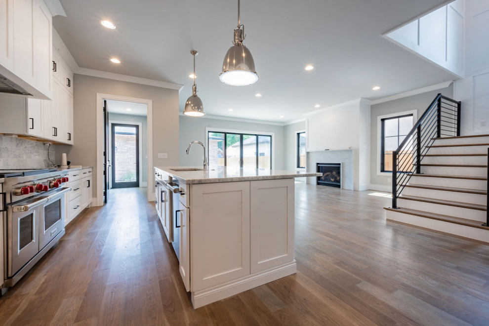 Inspiration for a transitional single-wall medium tone wood floor eat-in kitchen remodel in Denver with an undermount sink, shaker cabinets, white cabinets, gray backsplash, marble backsplash, stainless steel appliances, an island and white countertops
