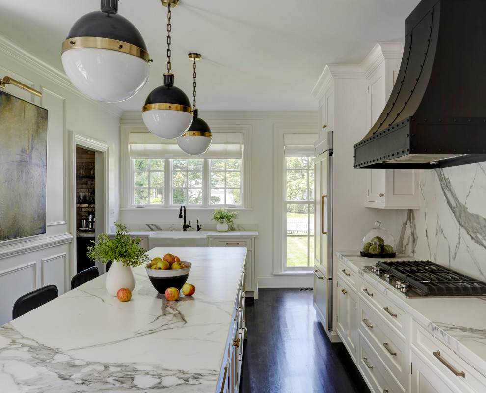Klassisk inredning av ett avskilt, mellanstort vit vitt l-kök, med en rustik diskho, luckor med infälld panel, vita skåp, bänkskiva i kvarts, vitt stänkskydd, stänkskydd i sten, integrerade vitvaror, mörkt trägolv, en köksö och svart golv