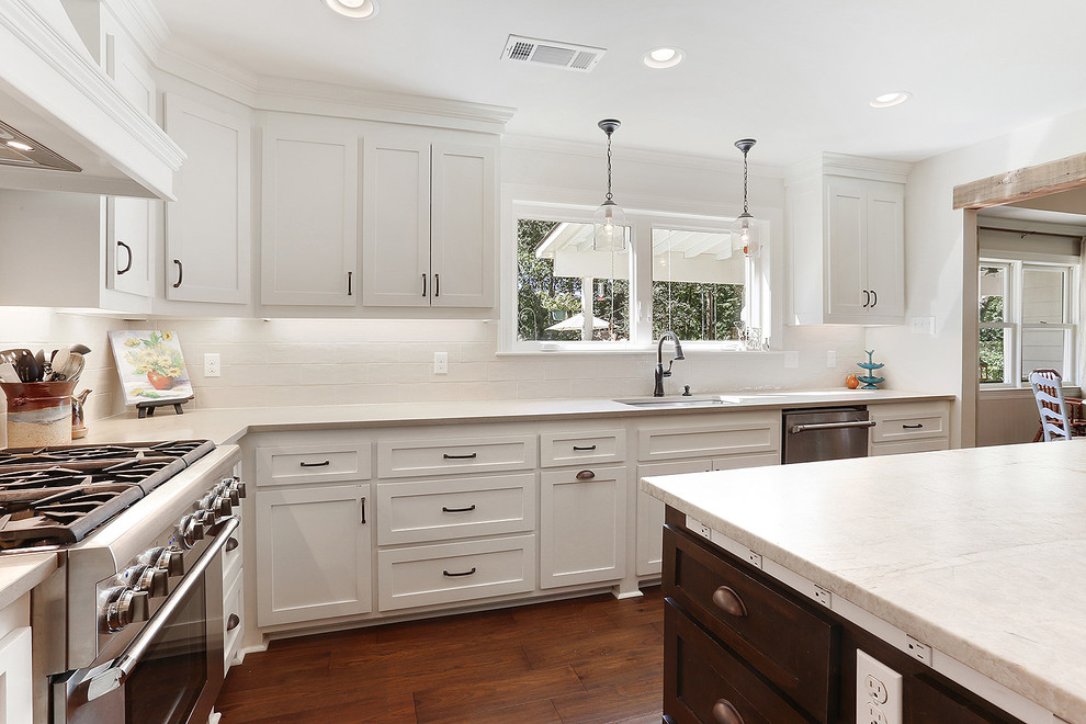 Example of a large transitional medium tone wood floor and brown floor eat-in kitchen design in New Orleans with an undermount sink, shaker cabinets, white cabinets, quartzite countertops, white backsplash, subway tile backsplash, stainless steel appliances and an island