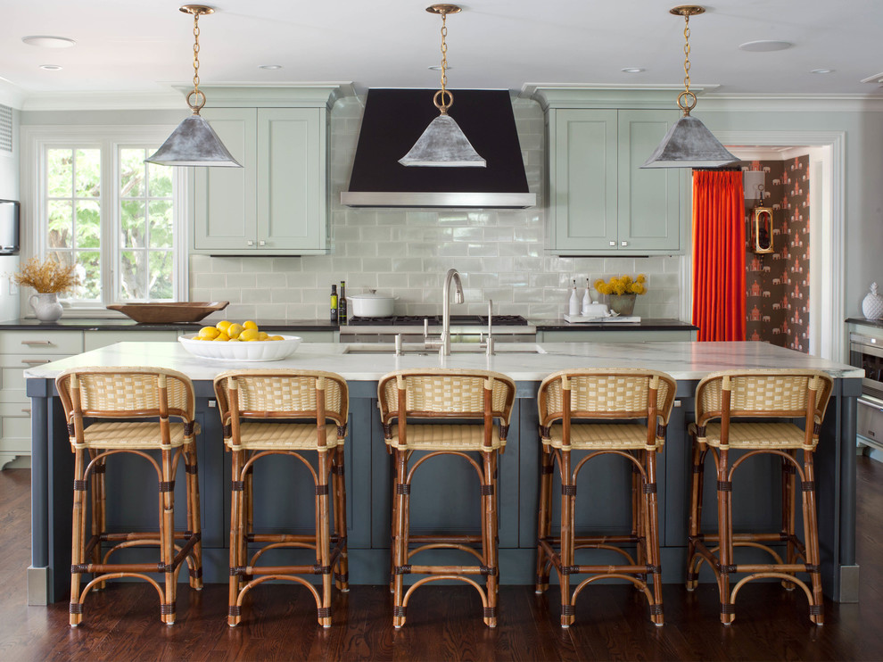 Exempel på ett stort klassiskt l-kök, med en undermonterad diskho, luckor med infälld panel, gröna skåp, marmorbänkskiva, vitt stänkskydd, stänkskydd i glaskakel, rostfria vitvaror, mörkt trägolv och en köksö