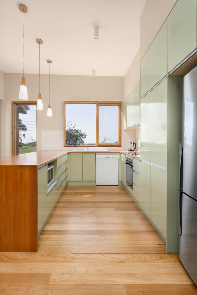 Mittelgroße Moderne Wohnküche in L-Form mit Doppelwaschbecken, Arbeitsplatte aus Holz, Küchenrückwand in Weiß, Rückwand aus Keramikfliesen und hellem Holzboden in Sonstige