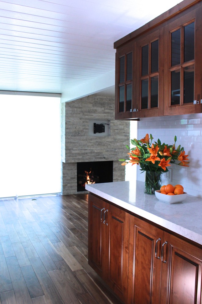 Esempio di una cucina minimalista di medie dimensioni con lavello sottopiano, ante con bugna sagomata, ante in legno scuro, top in quarzo composito, elettrodomestici in acciaio inossidabile e pavimento in legno massello medio