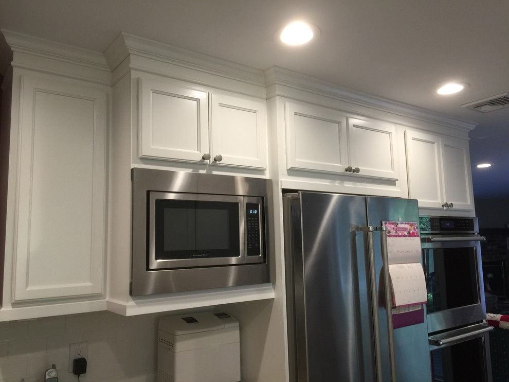 Foto de cocina clásica con armarios estilo shaker, puertas de armario blancas, electrodomésticos de acero inoxidable y península