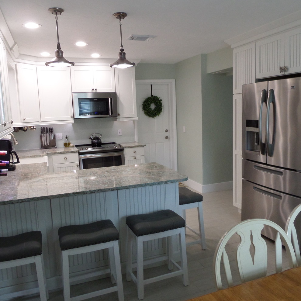 Example of a beach style u-shaped ceramic tile eat-in kitchen design in Orlando with a farmhouse sink, beaded inset cabinets, white cabinets, quartz countertops, stainless steel appliances and no island
