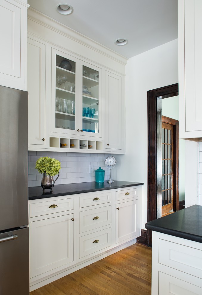 Klassische Küche mit Landhausspüle, Küchenrückwand in Weiß, Rückwand aus Keramikfliesen, Küchengeräten aus Edelstahl, Kücheninsel und braunem Holzboden in Atlanta