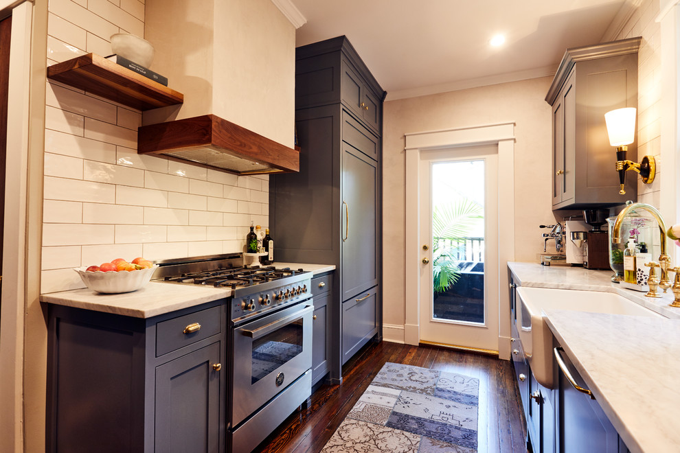 Photo of a small classic galley enclosed kitchen in Atlanta with a belfast sink, shaker cabinets, blue cabinets, white splashback, metro tiled splashback, stainless steel appliances, medium hardwood flooring, no island and marble worktops.