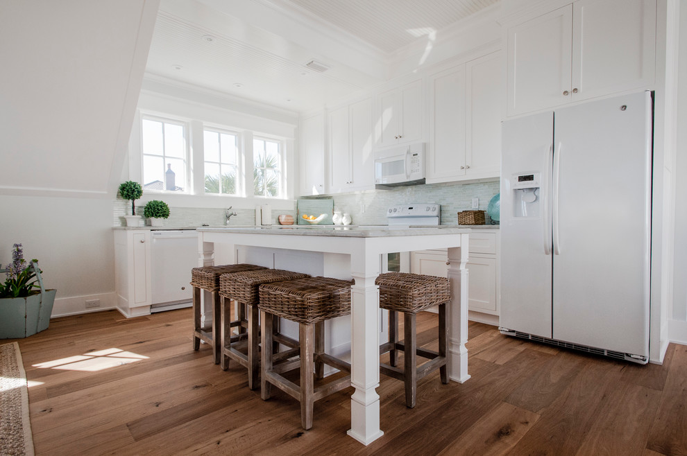 Exempel på ett litet klassiskt kök, med en undermonterad diskho, luckor med infälld panel, vita skåp, marmorbänkskiva, grått stänkskydd, stänkskydd i stickkakel, vita vitvaror, mellanmörkt trägolv och en köksö