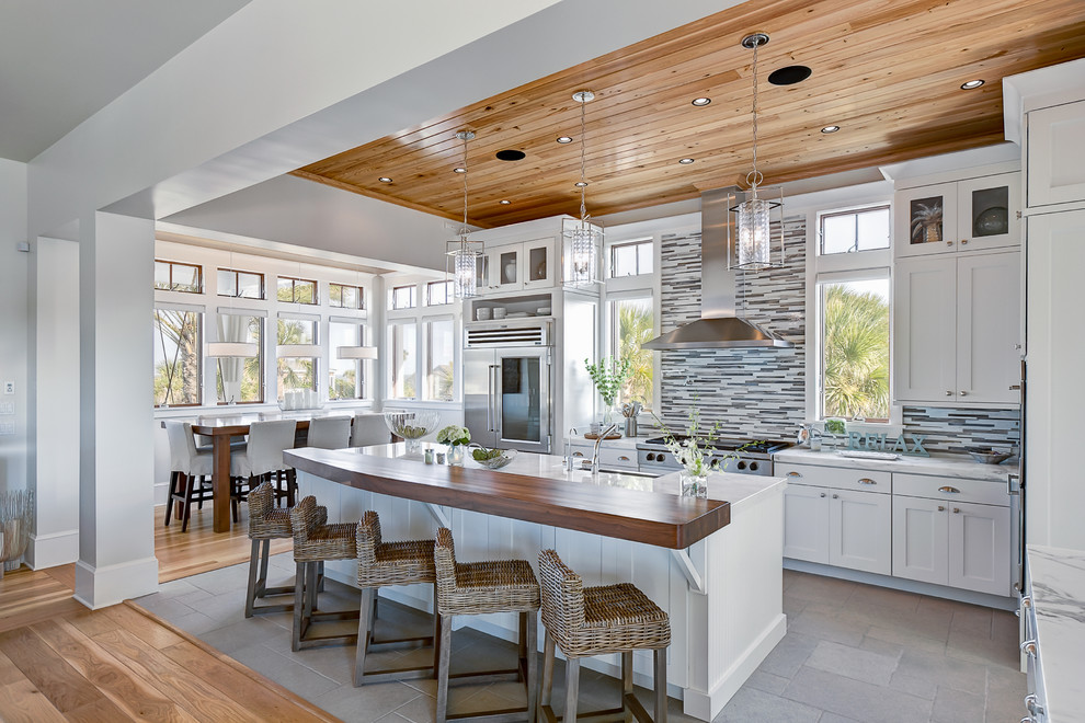 Example of a beach style l-shaped kitchen design in Jacksonville with matchstick tile backsplash, marble countertops, shaker cabinets, white cabinets, stainless steel appliances and multicolored backsplash
