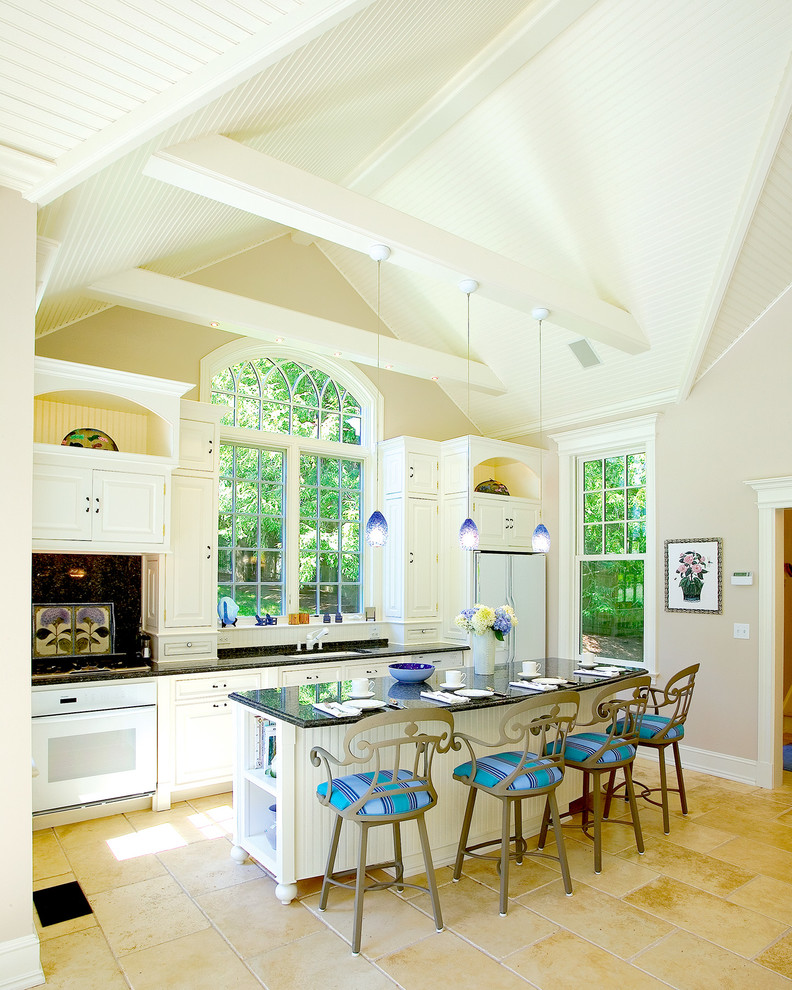 Exempel på ett mellanstort klassiskt kök, med en undermonterad diskho, luckor med profilerade fronter, vita skåp, granitbänkskiva, svart stänkskydd, stänkskydd i sten, vita vitvaror, kalkstensgolv och en köksö