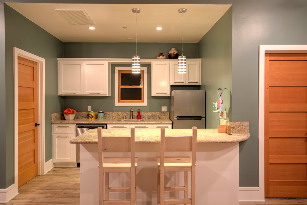 Foto på ett litet funkis kök, med en undermonterad diskho, skåp i shakerstil, skåp i ljust trä, granitbänkskiva, rostfria vitvaror, klinkergolv i porslin och en halv köksö