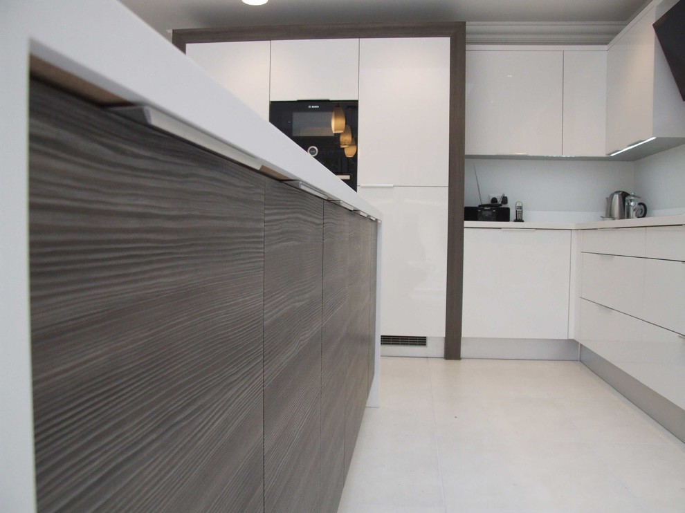 Medium sized contemporary l-shaped kitchen/diner in Dorset with a single-bowl sink, flat-panel cabinets, white cabinets, composite countertops, black splashback, glass sheet splashback, black appliances, ceramic flooring and an island.