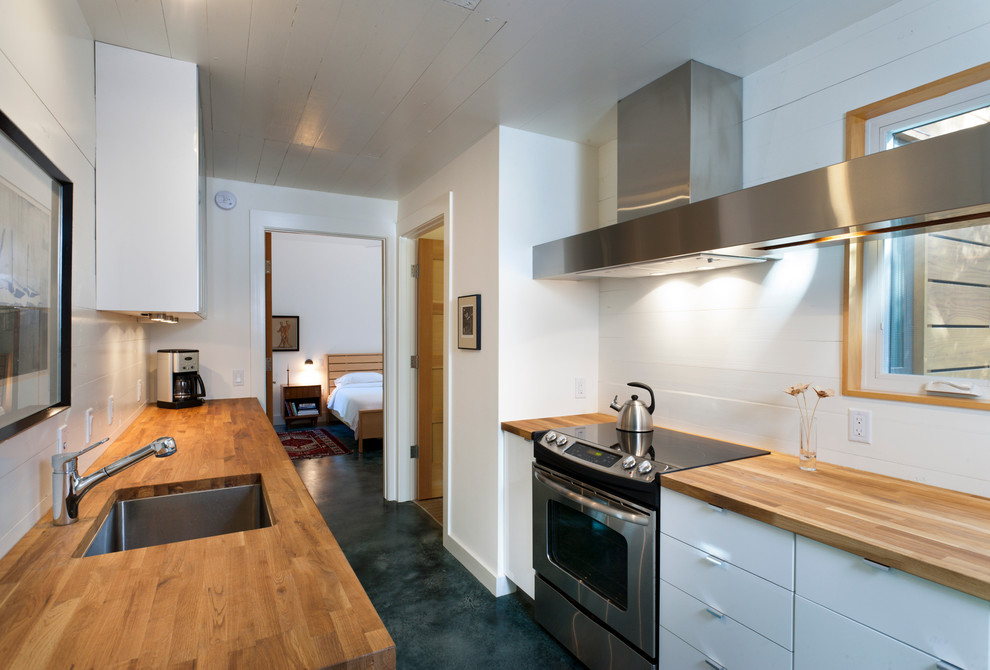 Идея дизайна: параллельная, отдельная кухня в современном стиле с деревянной столешницей, врезной мойкой, плоскими фасадами, белыми фасадами и окном