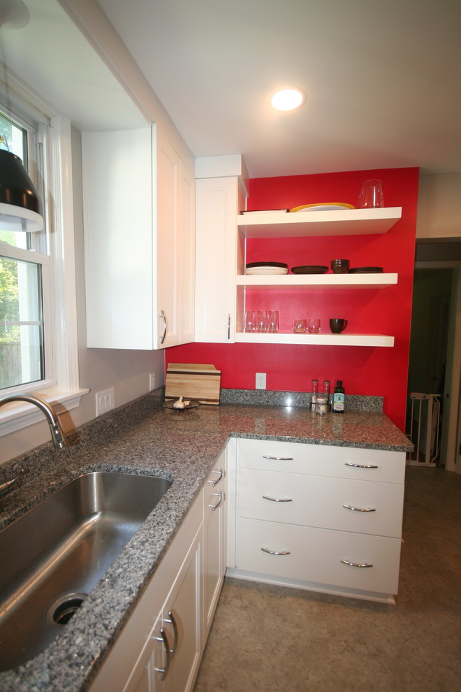 Ejemplo de cocina actual con puertas de armario blancas, salpicadero rojo y electrodomésticos de acero inoxidable