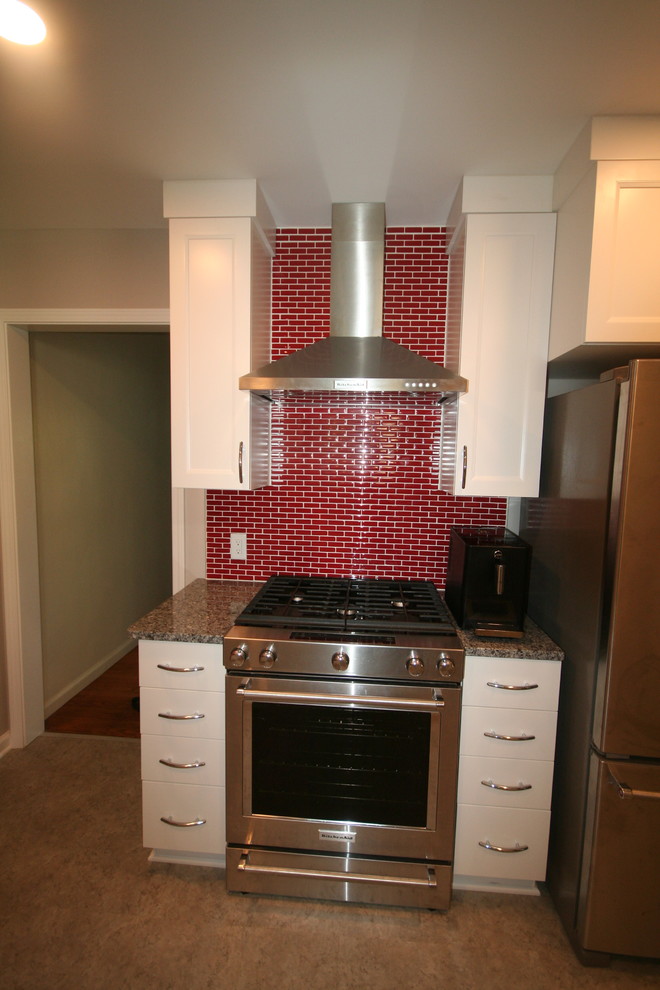 Пример оригинального дизайна: кухня в современном стиле с белыми фасадами, красным фартуком и техникой из нержавеющей стали