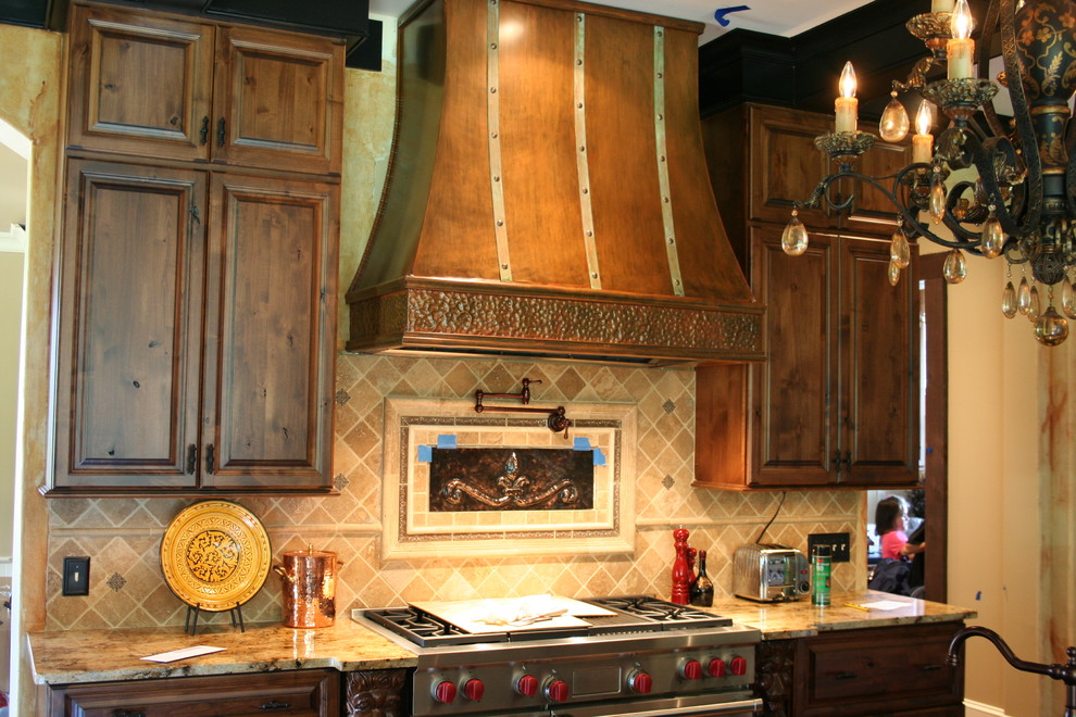 Aménagement d'une grande cuisine américaine montagne en bois brun avec un plan de travail en granite, un électroménager en acier inoxydable, un placard avec porte à panneau surélevé, une crédence beige et une crédence en mosaïque.