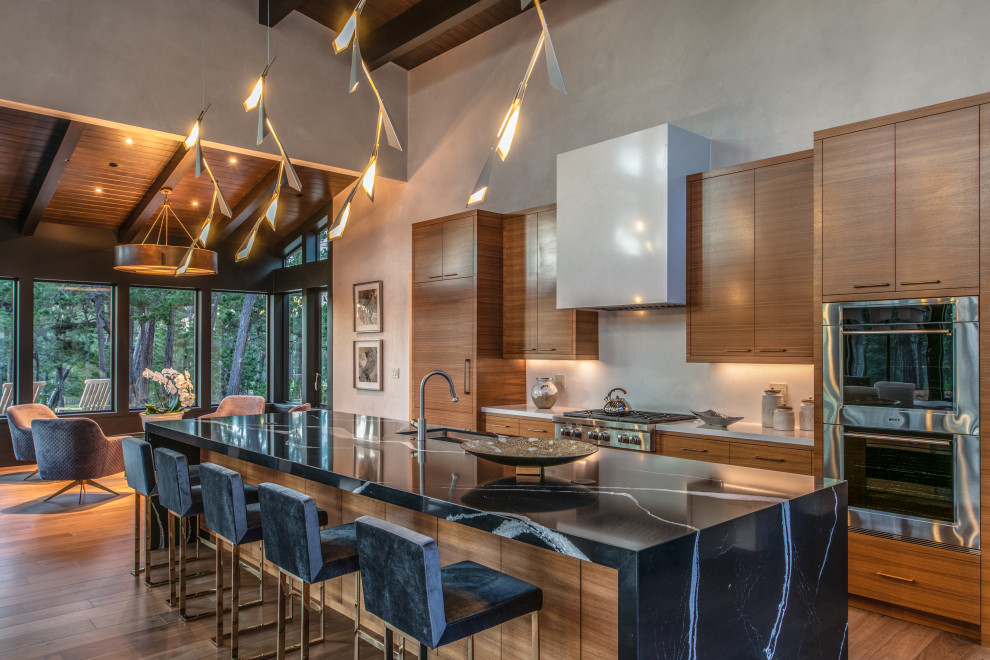 Trendy galley medium tone wood floor, brown floor, exposed beam and wood ceiling open concept kitchen photo in Other with an undermount sink, flat-panel cabinets, medium tone wood cabinets, white backsplash, paneled appliances, an island and multicolored countertops